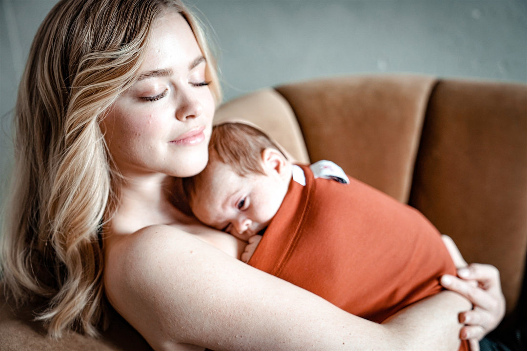 Mutter kuschelt mit ihrem Baby in einem rostfarbenen Bonding-Shirt